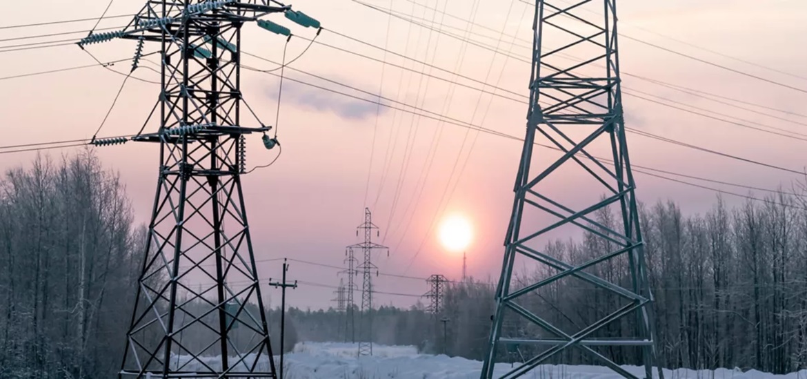 several power grid towers in the snow covered field in the sunset