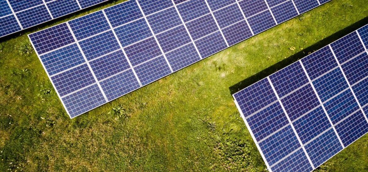 solar panels on a green field photographed from the bird perspective
