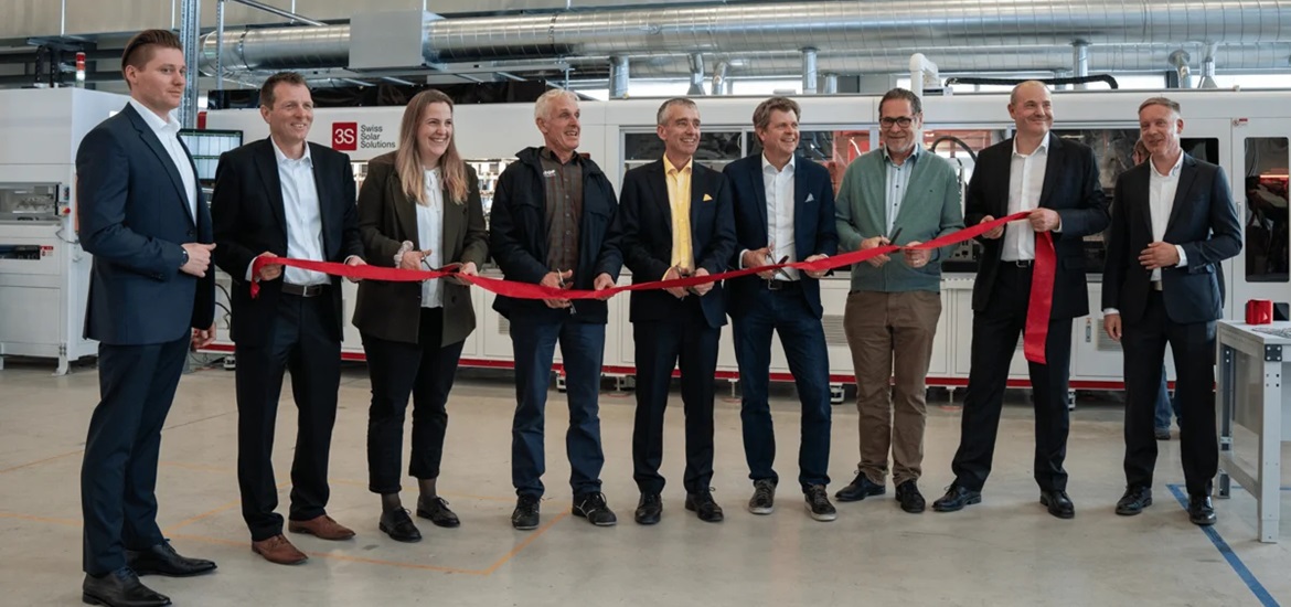 9 3s- Solar Swiss headquarter members holding a red ribbon and smiling to the camera