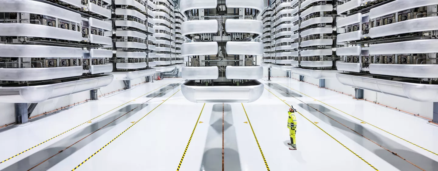 Photo of HVDC light valve hall and a man dressed in yellow maintenance uniform standing and looking up