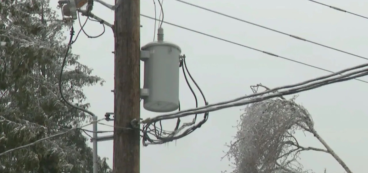 Power transformer on the wooden pole with frozen electric wires