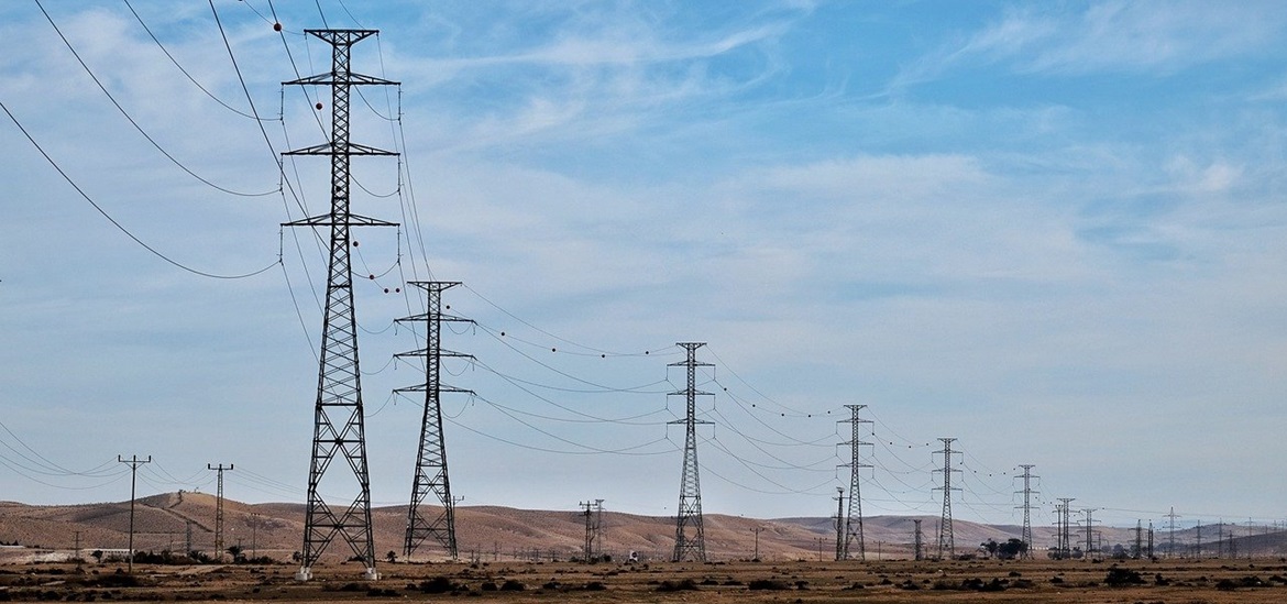power transmission towers on the land against blue sky