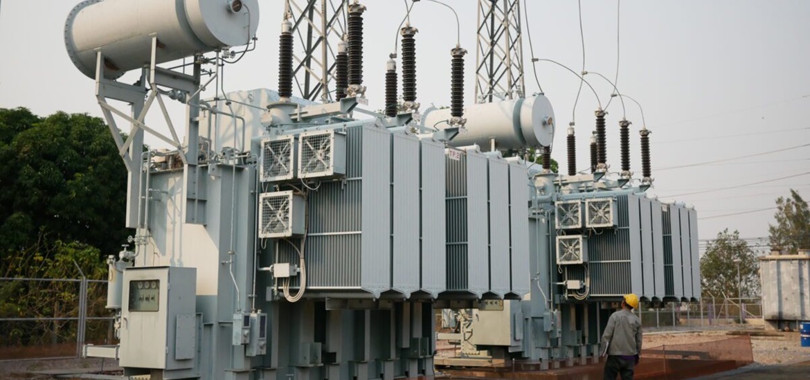Huge power transformer connected to the grid and a maintenance workor approaching it
