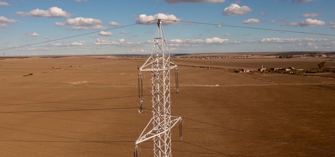 power tower connected with power lines and red soil field in the back