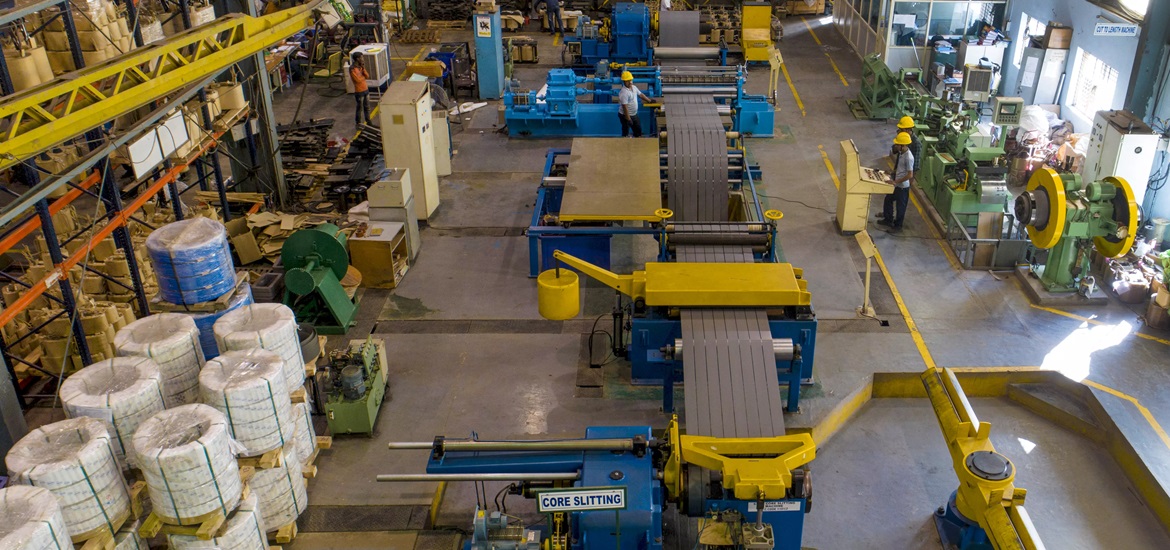 Photo of SSEL's manufacturing facility showing a couple of werkers, equipment, machines and coneyor belt at the centre of the facility  