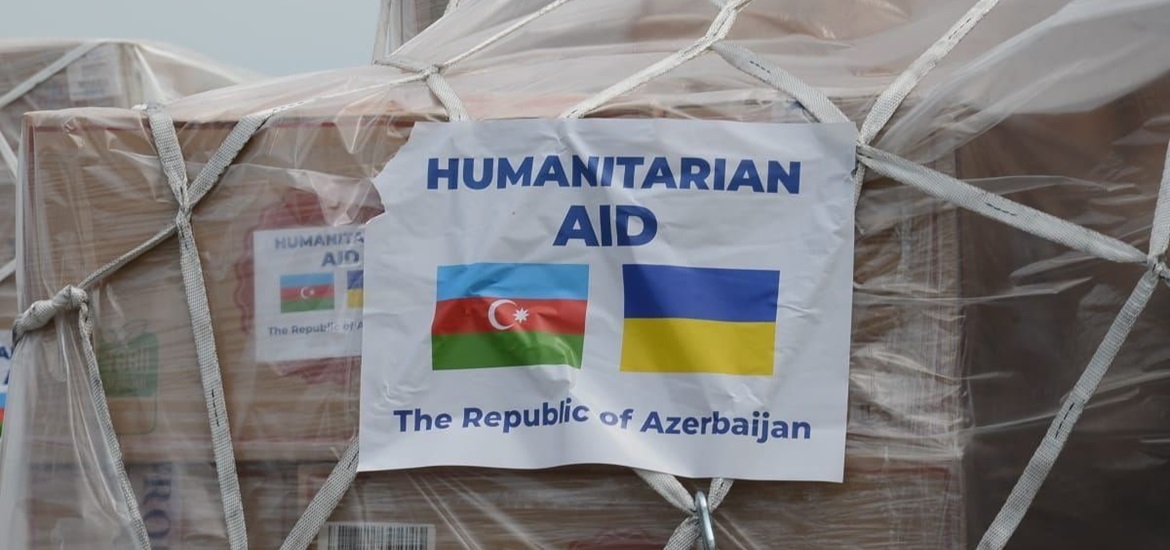 Cargo packed in brown carton boxes, protected with nylon and net, with a paper clipped to it, saying: Humanitarian Aid, The Republic of Azerbaijan and ukranian and azerbaijan flags