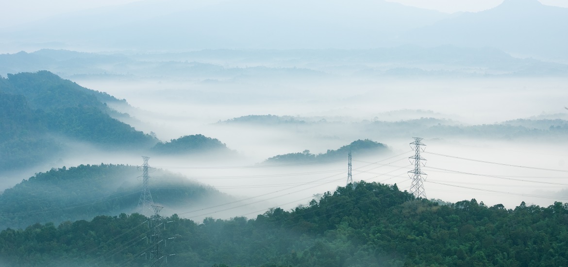 High voltage power transmission towers in fog on mountain mae moh lampang.