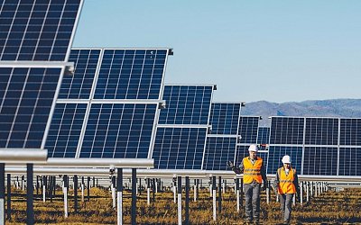 Two maintenance workers walking between solar panels on a solar farm